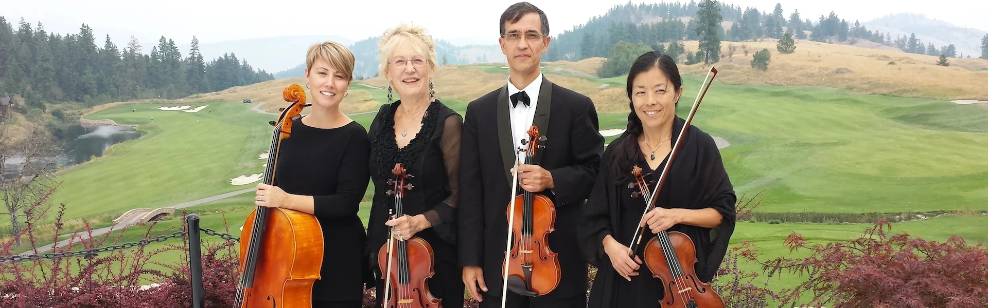 A string quartet poses in front of the grassy hill of a golf course.