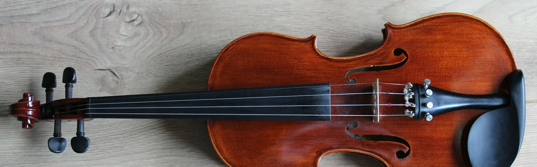 A horizontal violin against a grey wood background.